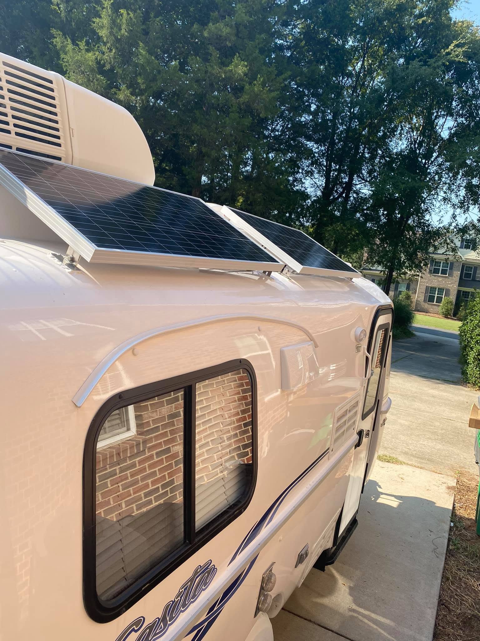 Angled Renogy solar panel mounted beside the Casita rooftop air conditioner