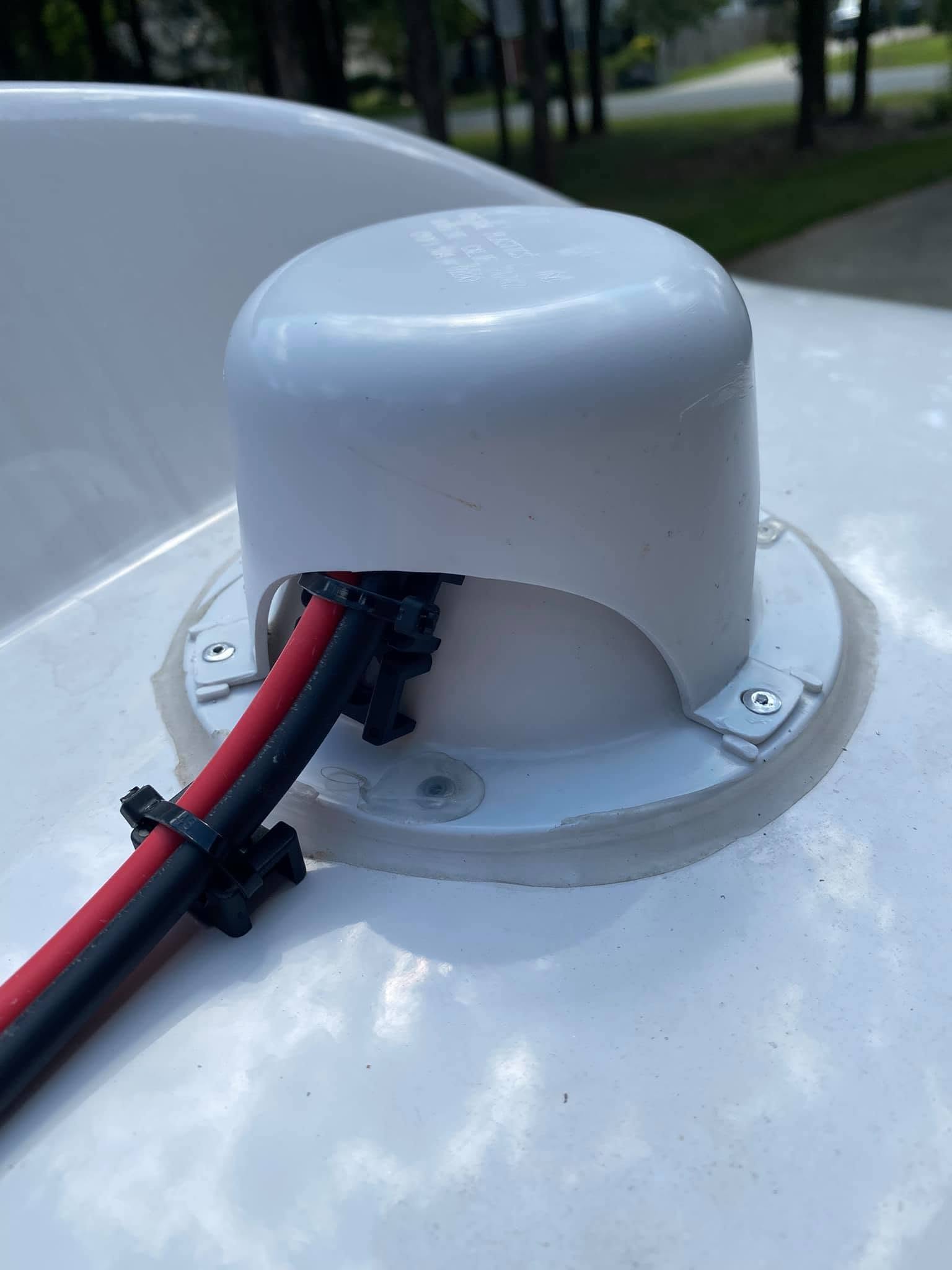 Red and black solar cables entering the roof through a gray vent cap