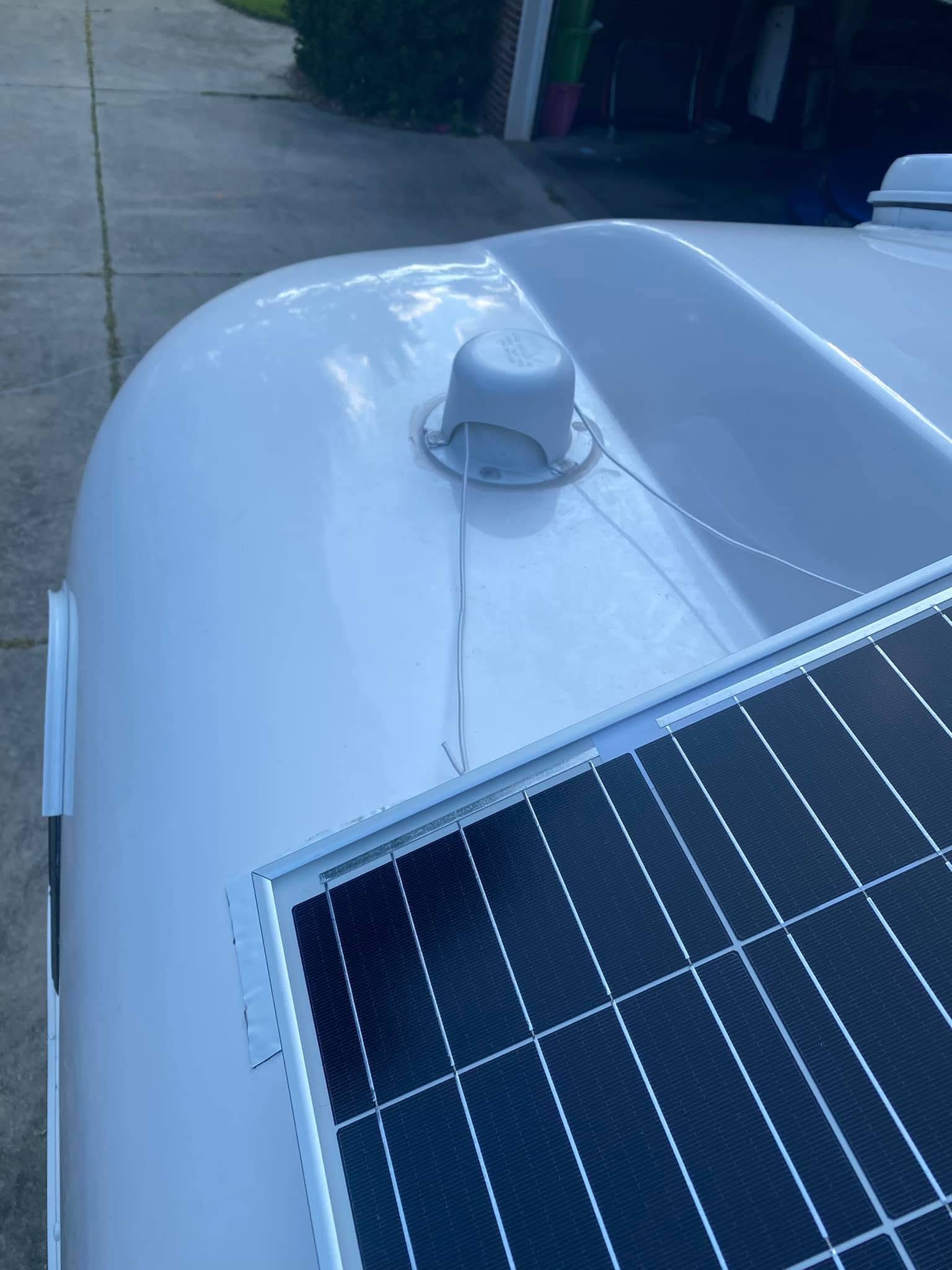 Solar panel foot and safety tether beside a roof vent cap